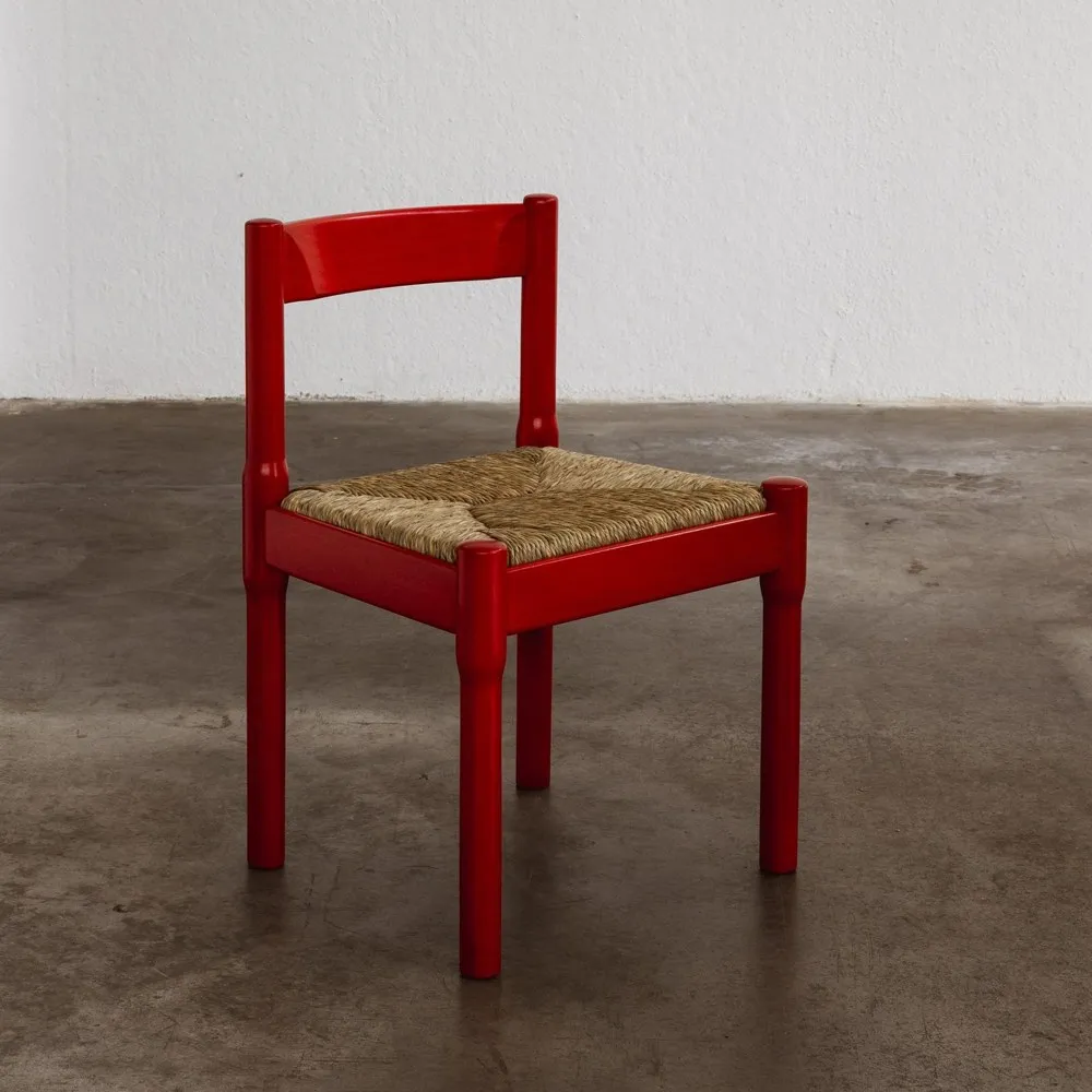 A red lacquered dining chair with a rush seat