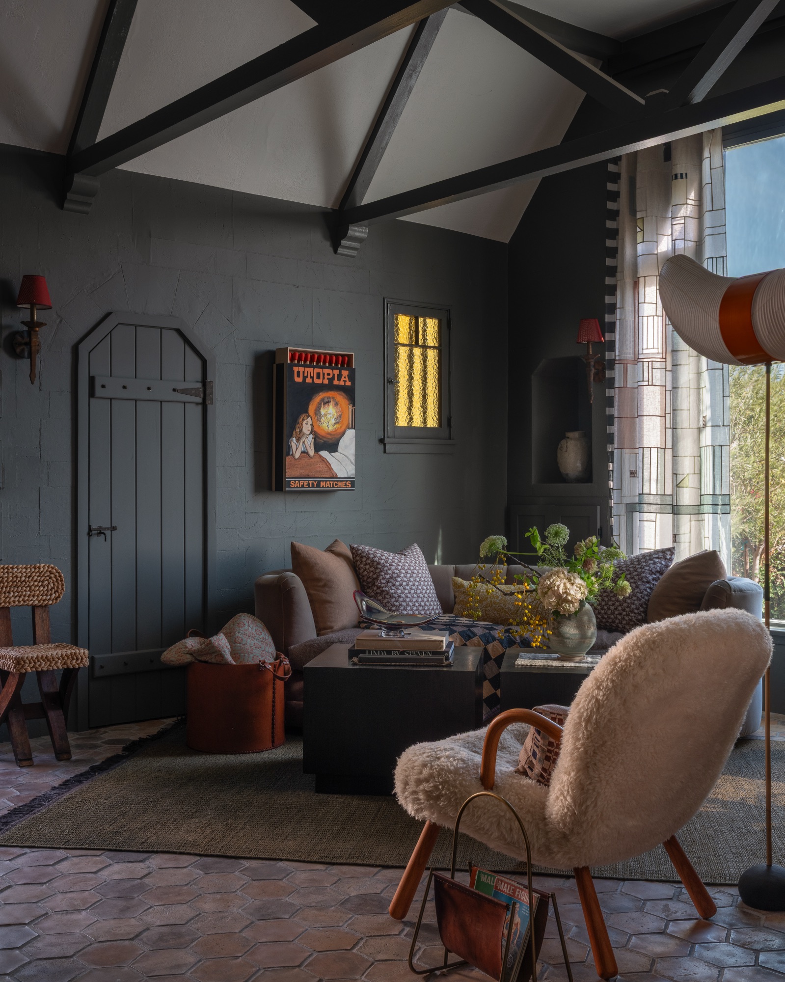 A living room by Charlie Barstein: deep green walls, black beams, a shearling chair