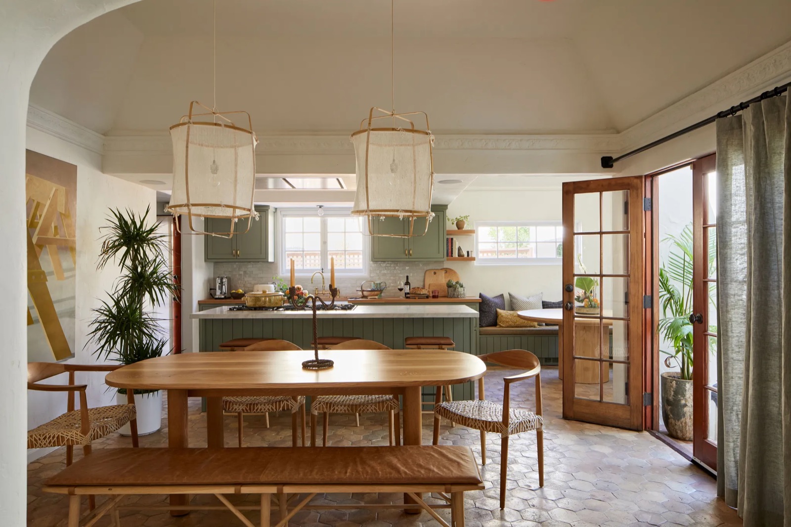 A kitchen and dining room with woven pendants and terracotta floors, a project by Charlie Barstein
