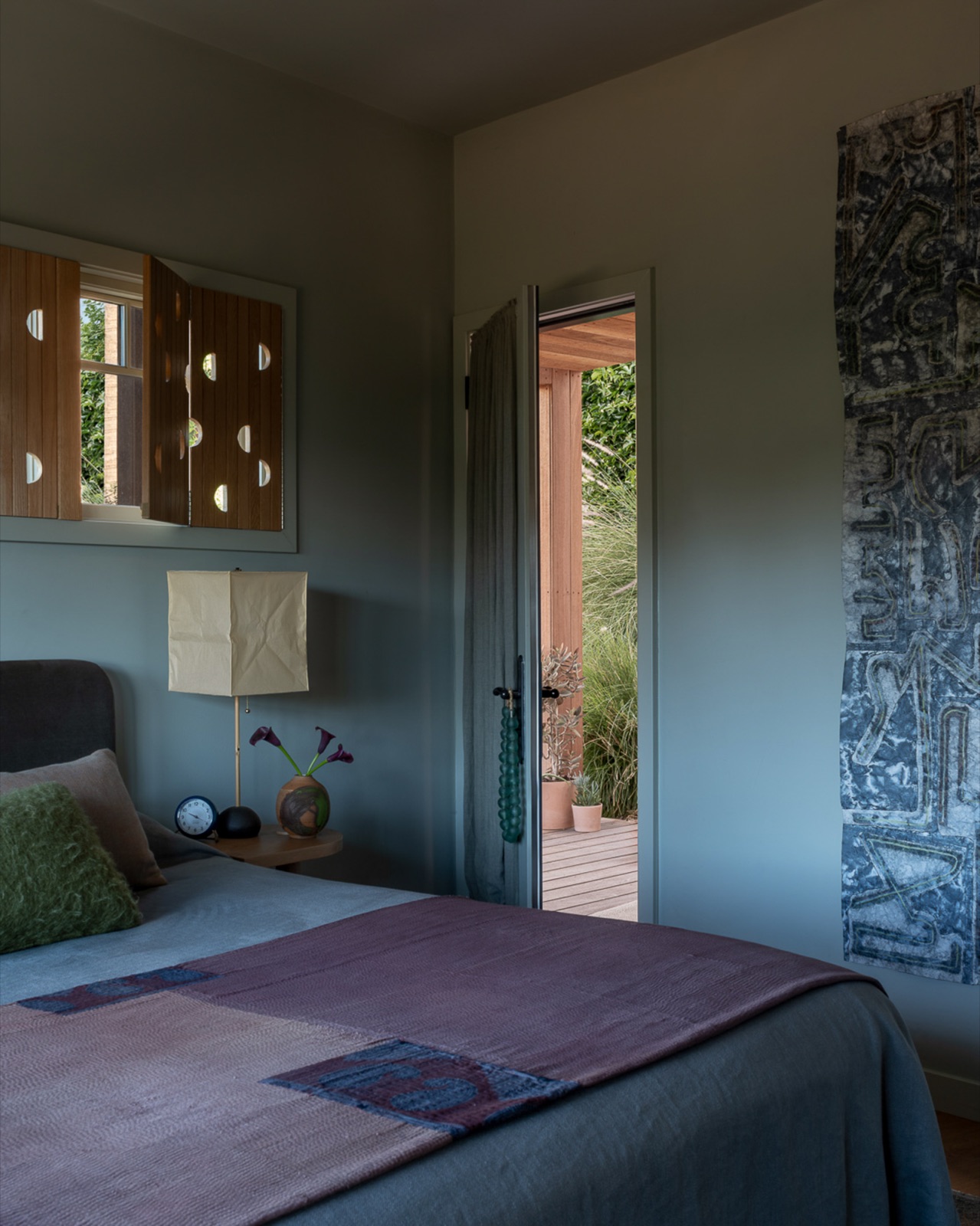 A bedroom in sage and plum, opening to a garden deck, a project by Charlie Barstein